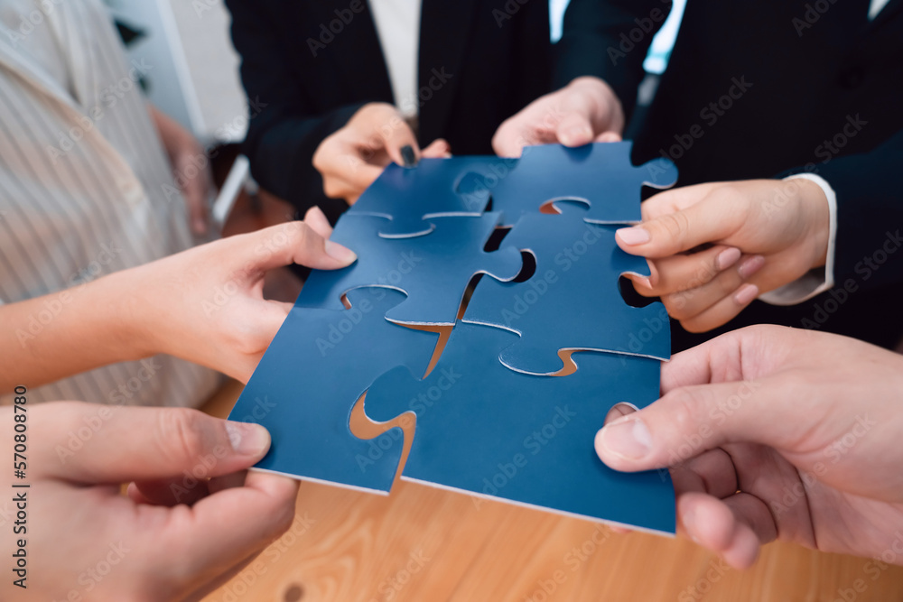 Closeup top view business team of office worker putting jigsaw puzzle together over table filled wit