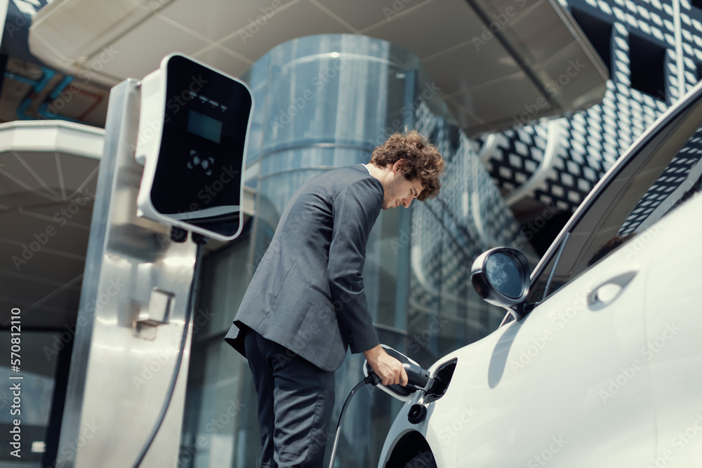 Below view closeup image of progressive black suit businessman recharge battery of his electric vehi