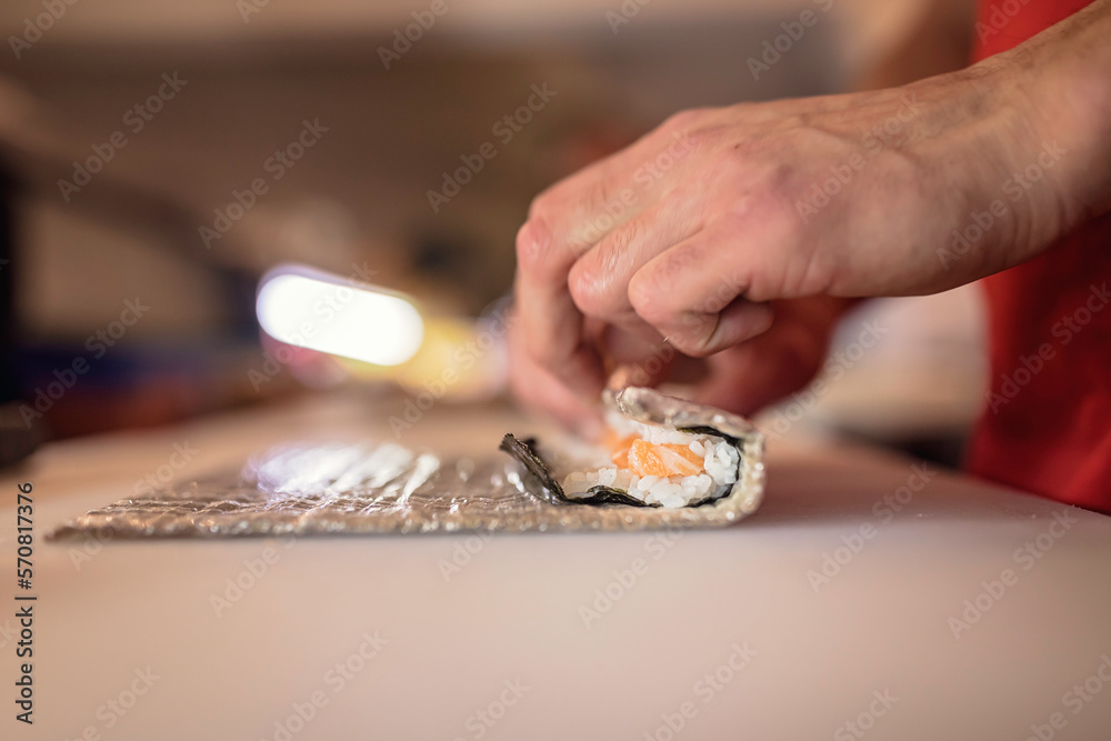 Expert sushi chef carefully cuts fresh salmon for delicious rolls. Perfect for food seafood photogra