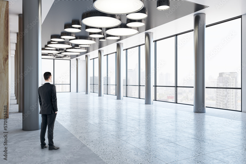 Man in black suit looking on city skyscrapers on background from business center high floor stylish 