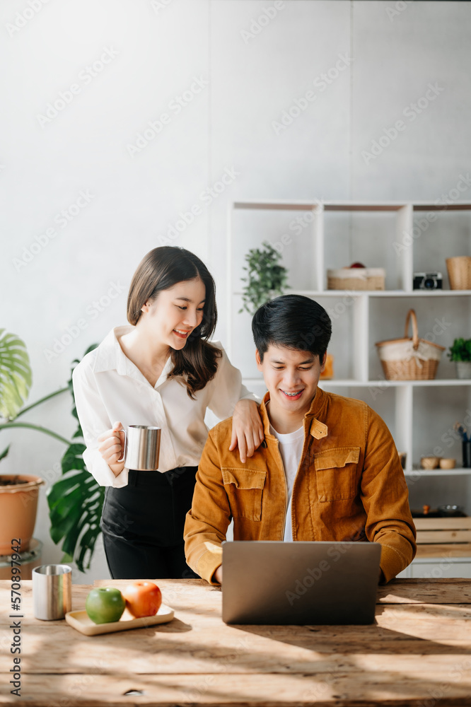 Two Asian business workers talking on the smartphone and using laptop at the home office.