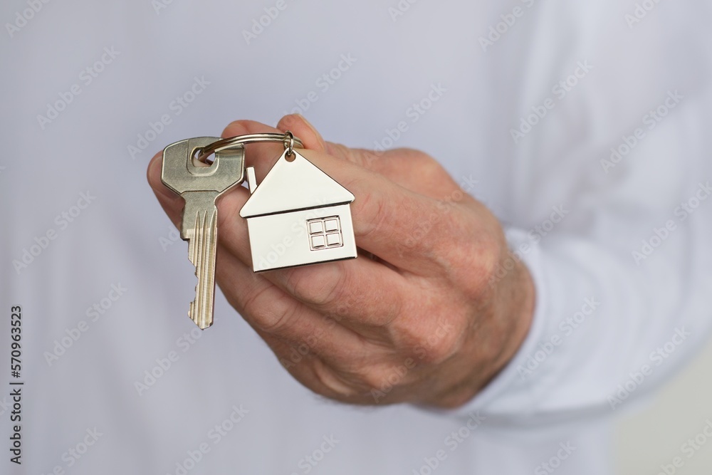 Mans hand holding a house key. Concept of buying a new house or home.