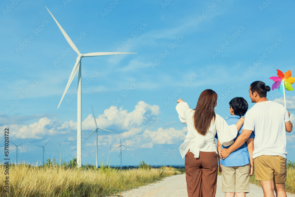 Concept of progressive happy family enjoying their time at the wind turbine farm. Electric generator