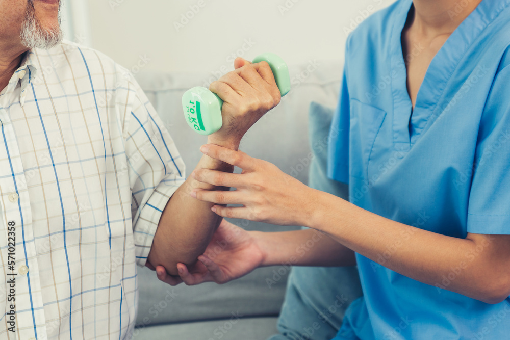 Contented senior patient doing physical therapy with the help of his caregiver. Senior physical ther