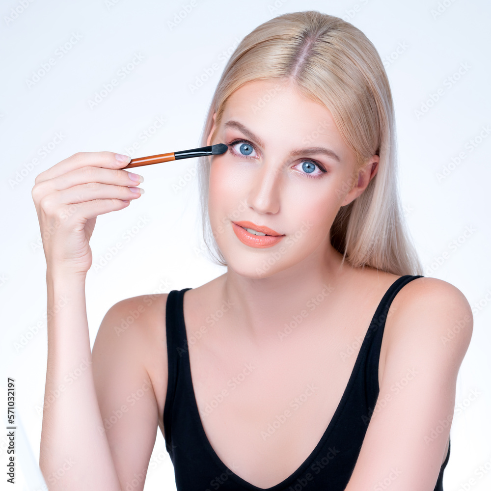 Closeup beautiful personable girl with flawless applying eye shadow makeup with eyeliner brush. Cosm