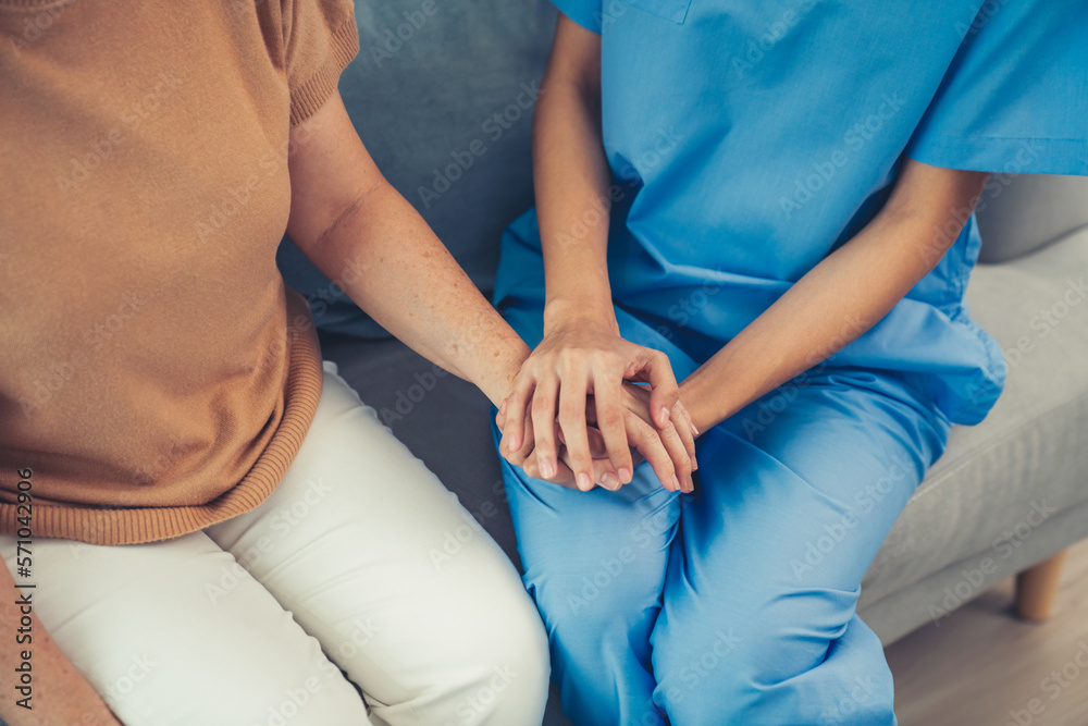 A contented senior woman visited by her personal caregiver and hold each others hands.