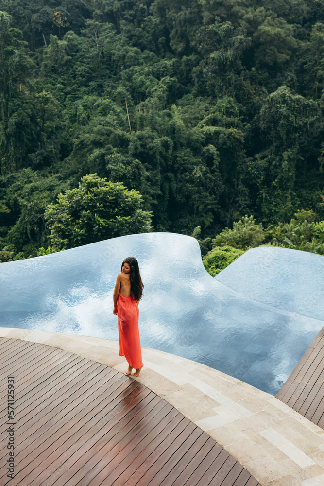 Young female standing by swimming pool