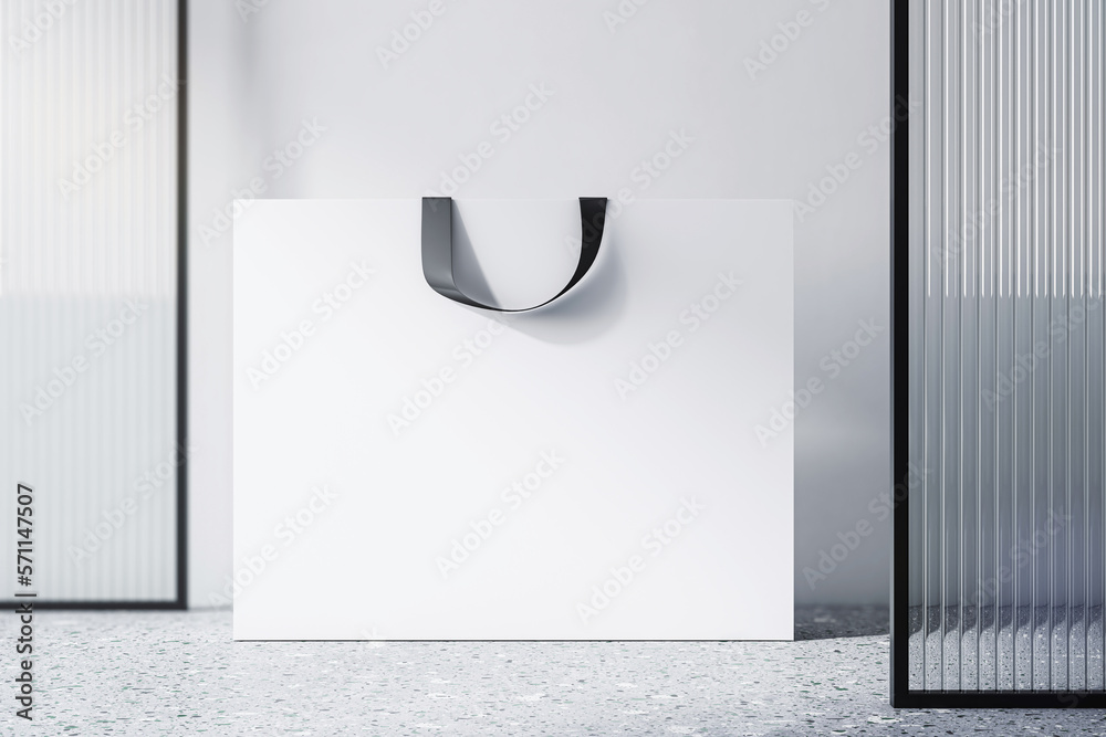 Front view on blank white paper shopping bag with place for your brand name or text on light concret