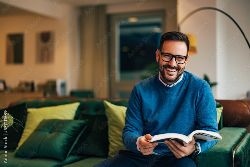 Portrait of a businessman holding a book, looking happy, and smiling for the camera.