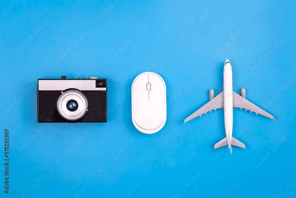 Vintage camera, computer mouse and airplane miniature on a blue background.