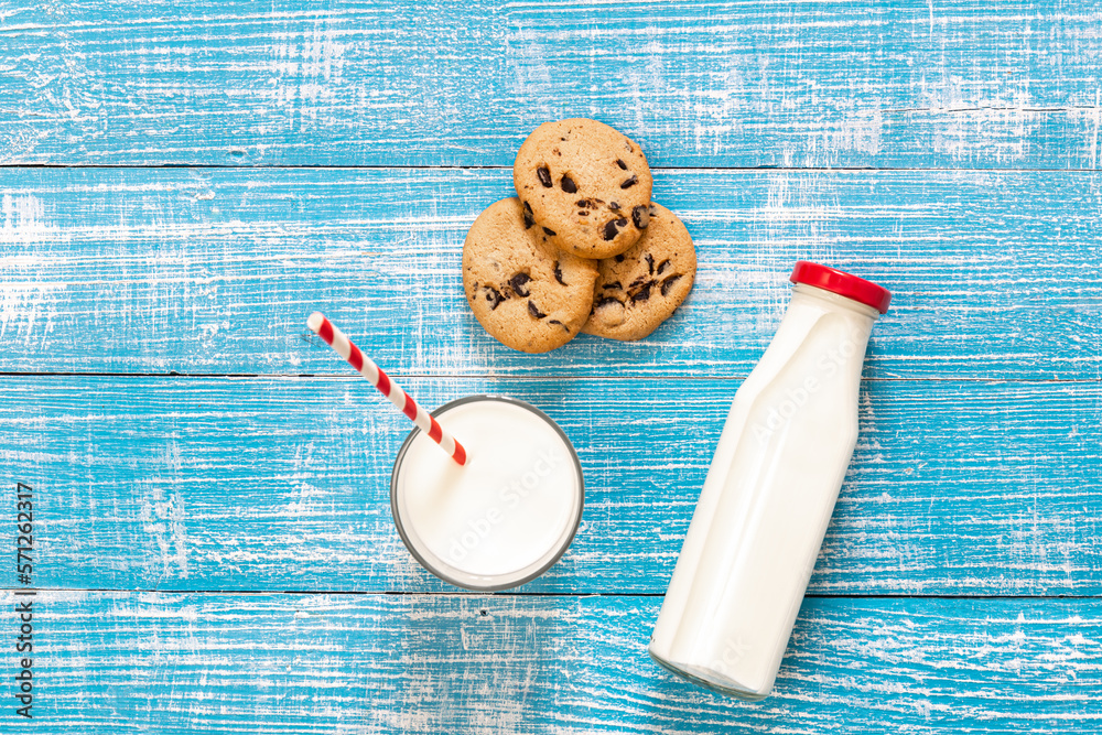 Bottle, cookies and glass with milk on a blue wooden background, flat lay.