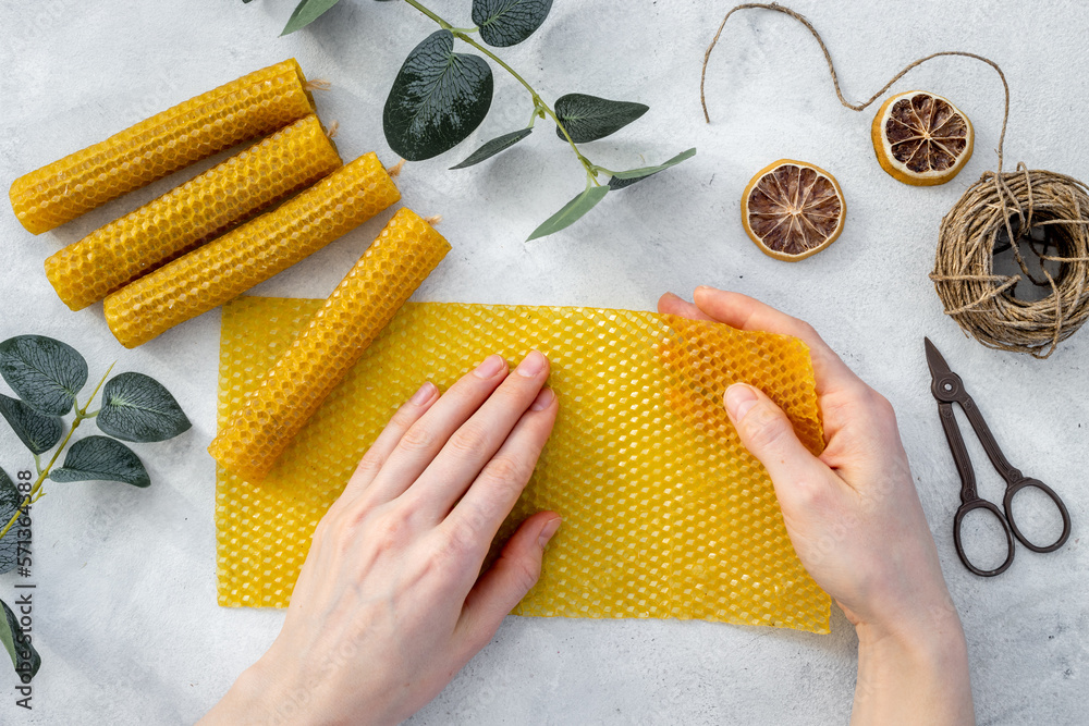 Hands making beeswax honey aroma candles with honeycombs, top view