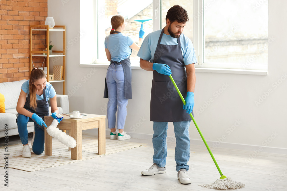 Young janitors cleaning in living room