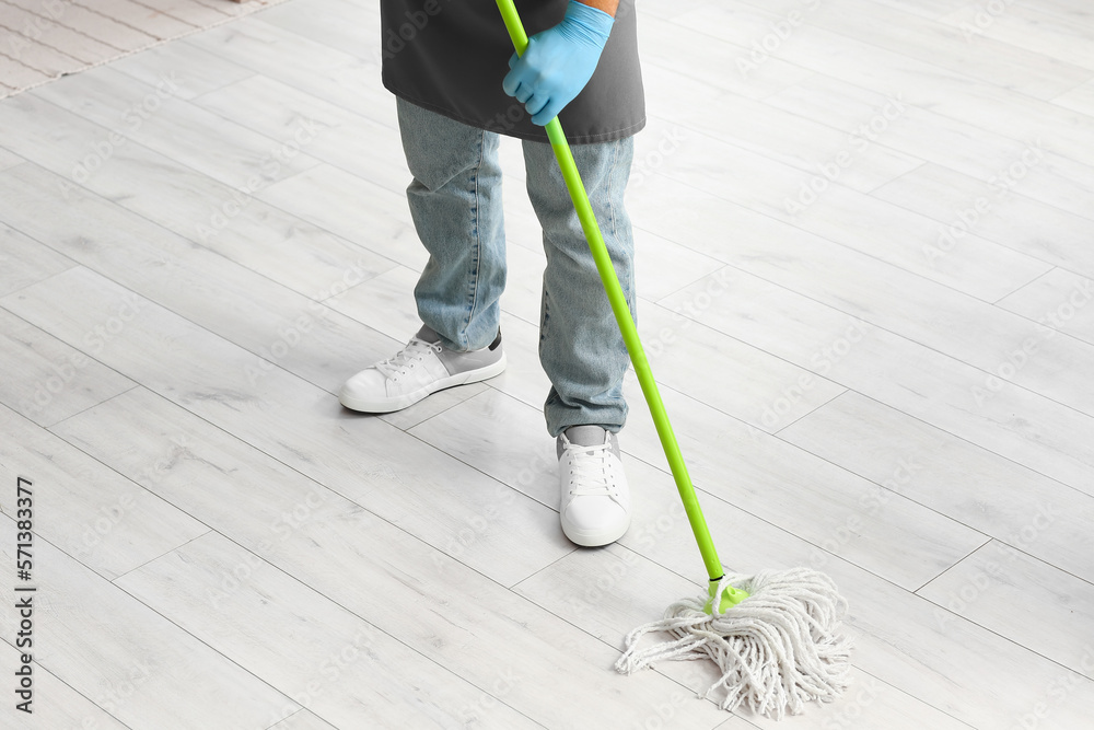 Male janitor mopping floor in living room