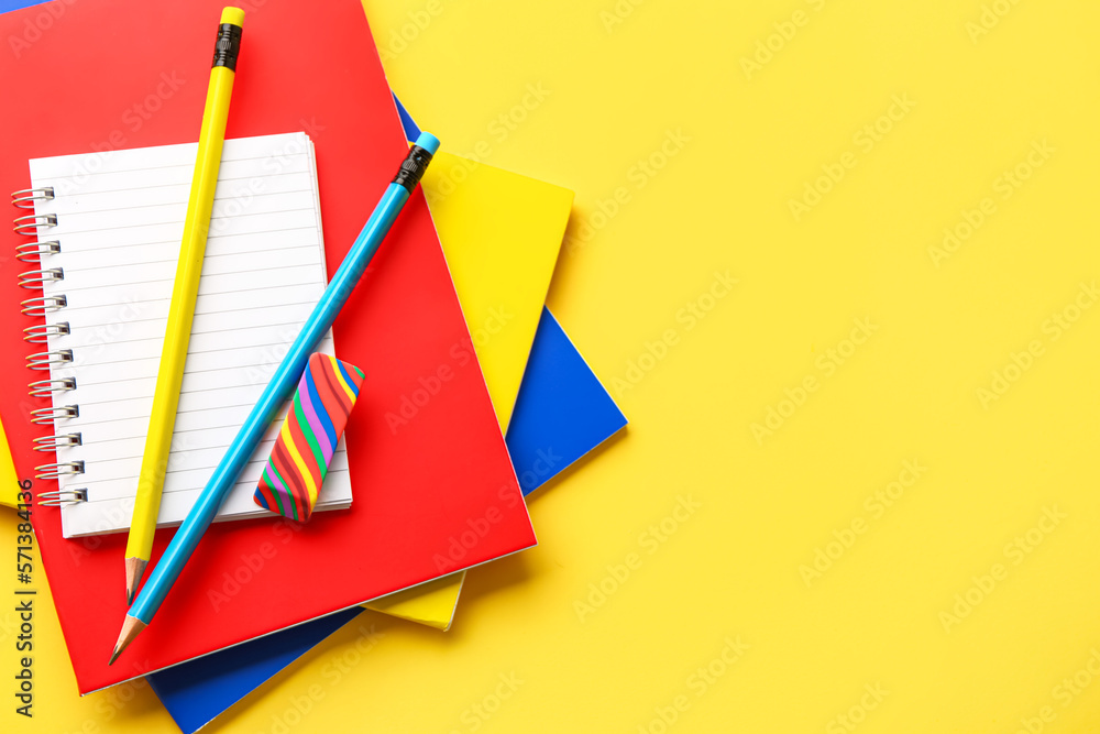 Notebooks, pencils and eraser on yellow background