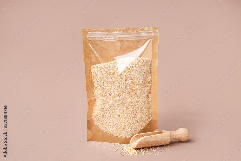 Paper bag and wooden scoop of amaranth seeds on color background