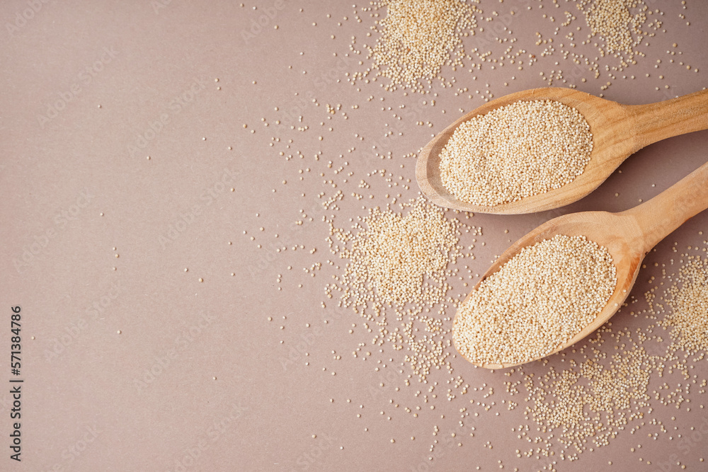 Wooden spoons of amaranth seeds on color background