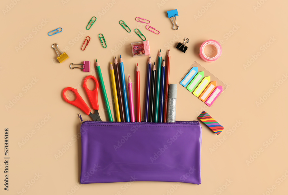 Case with colorful pencils and different stationery on color background