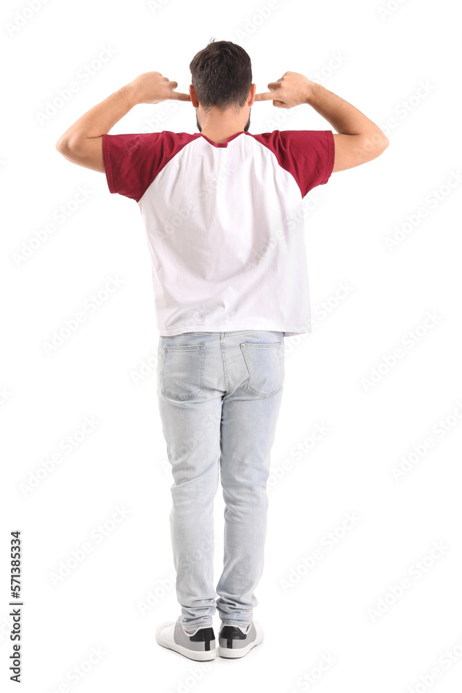 Young man suffering from loud noise on white background, back view