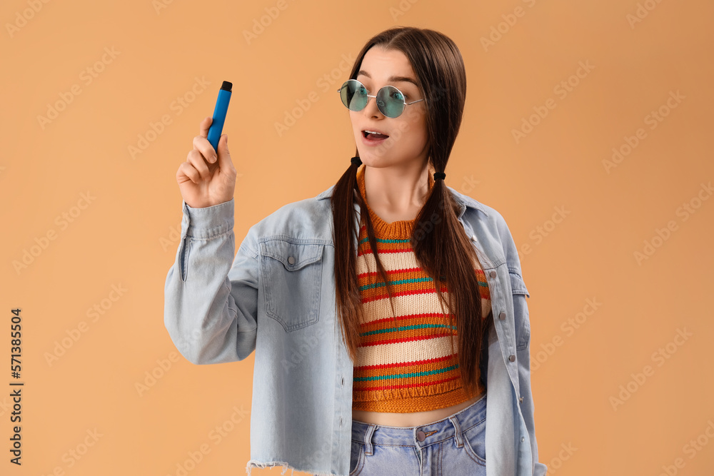 Young woman in sunglasses with disposable electronic cigarette on beige background