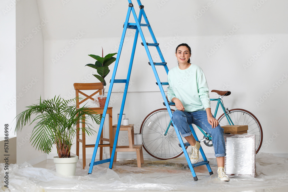 Young woman sitting on maintenance ladder at home