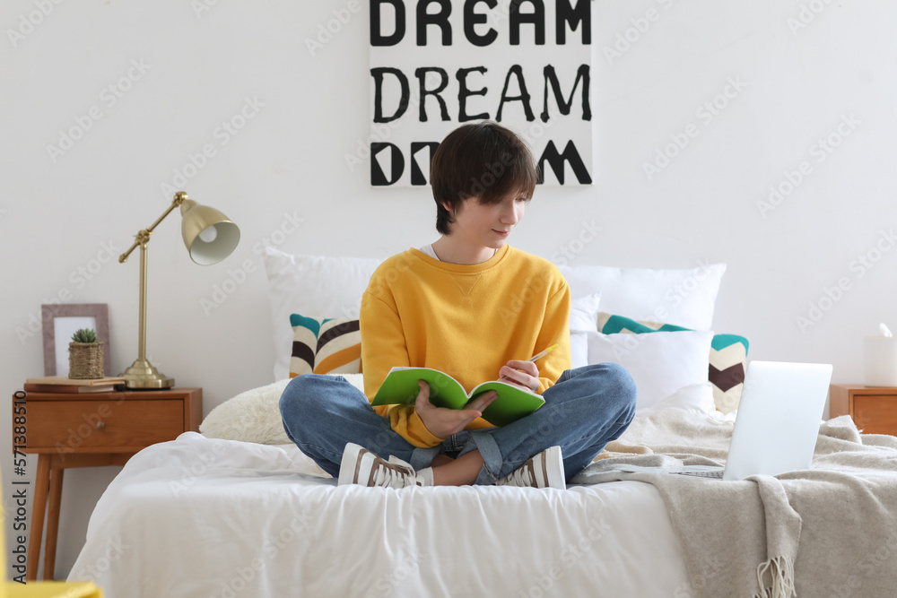 Male student with notebook studying online at home