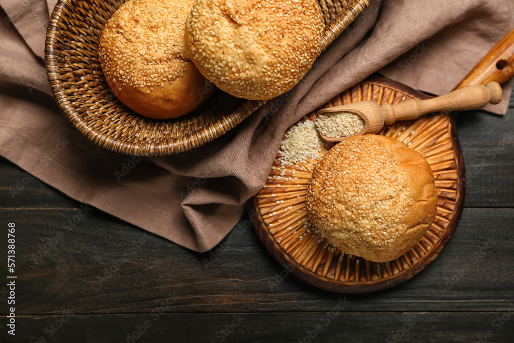 Wicker basket and board with delicious fresh buns on black wooden table