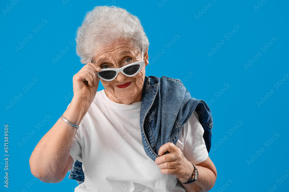 Senior woman in sunglasses on blue background