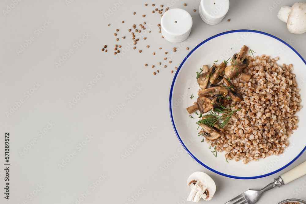 Plate of tasty buckwheat porridge with mushrooms and dill on grey background