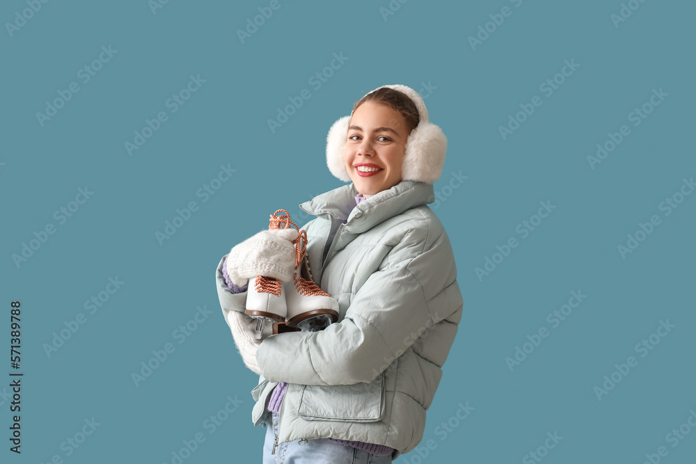 Pretty young woman with ice skates on blue background