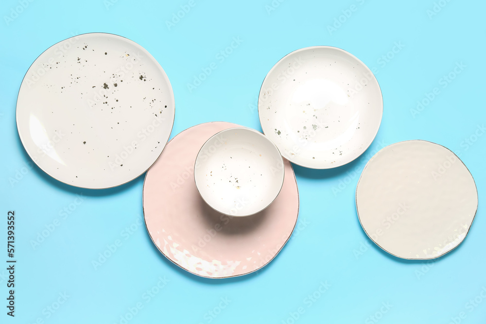 Set of empty ceramic plates on color background