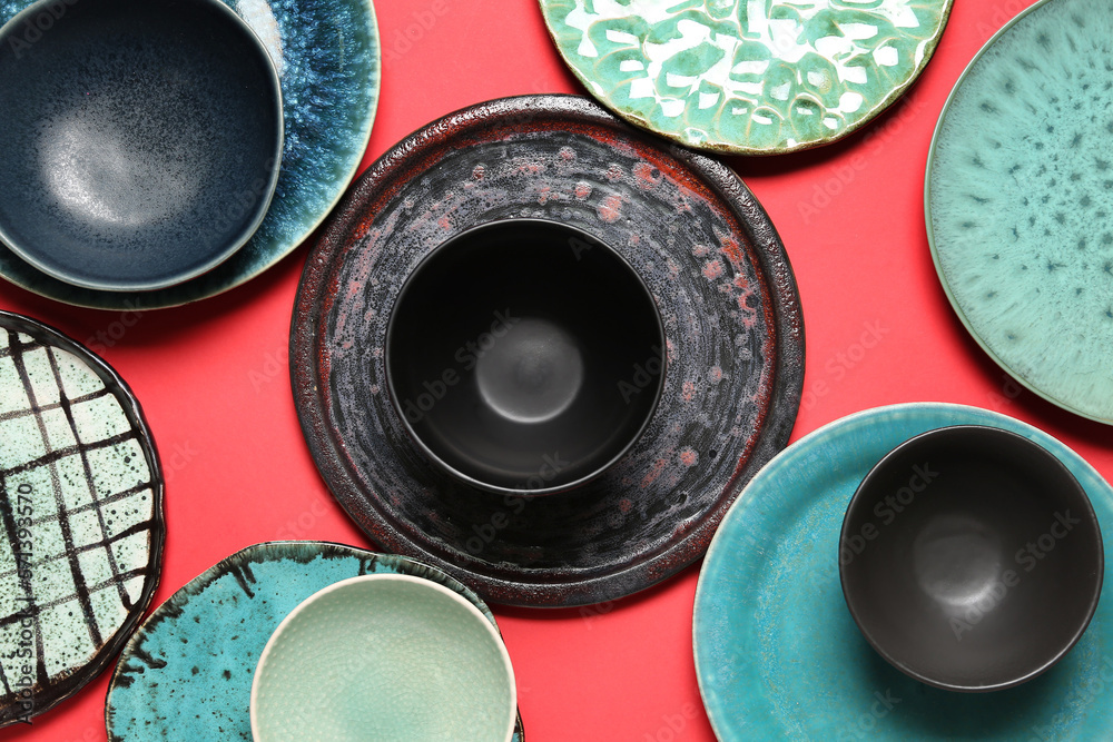 Set of stylish ceramic plates on red background, closeup