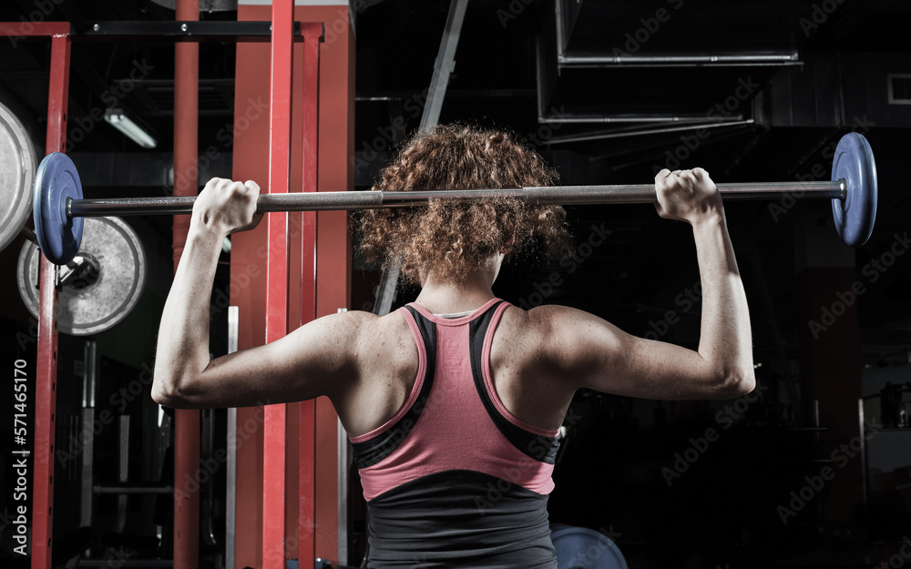 Woman bodybuilder engaged with a barbell in the gym