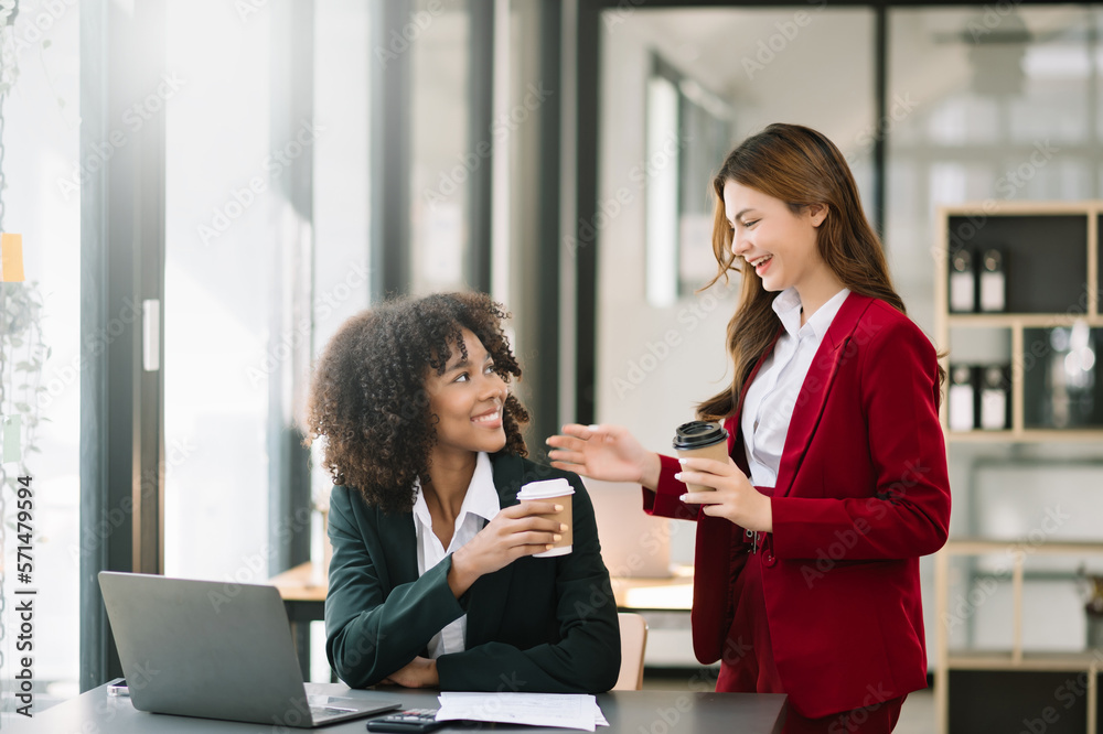 Happy two young business woman holding coffee cup in coworking office.