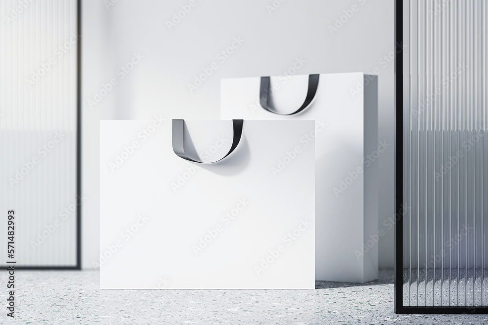 Front view on blank white paper shopping bags with space for your brand name or text on concrete flo