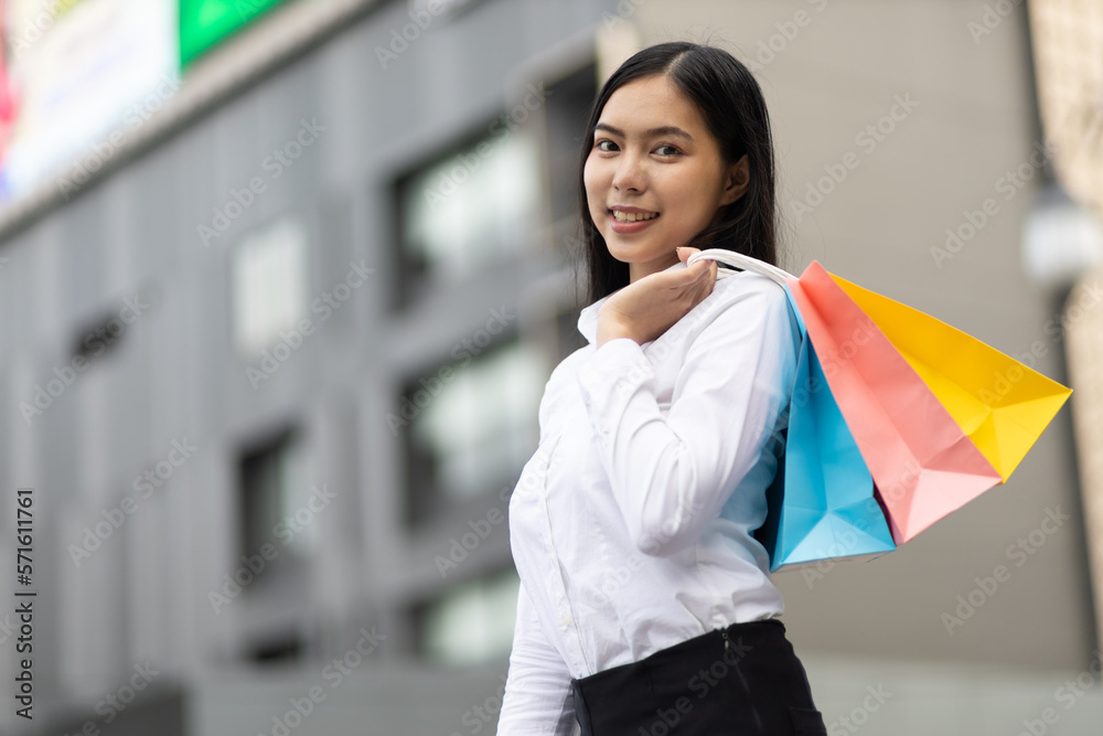 Cheerful and attractive young Asian woman carrying shopping bags. Female tourist carrying shopping b