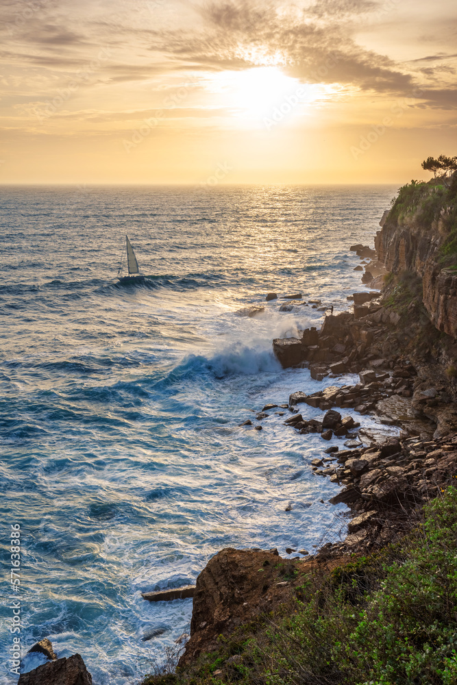 Beautiful colorful sunset and vivid dramatic sky at rocky shore of the Atlantic ocean.