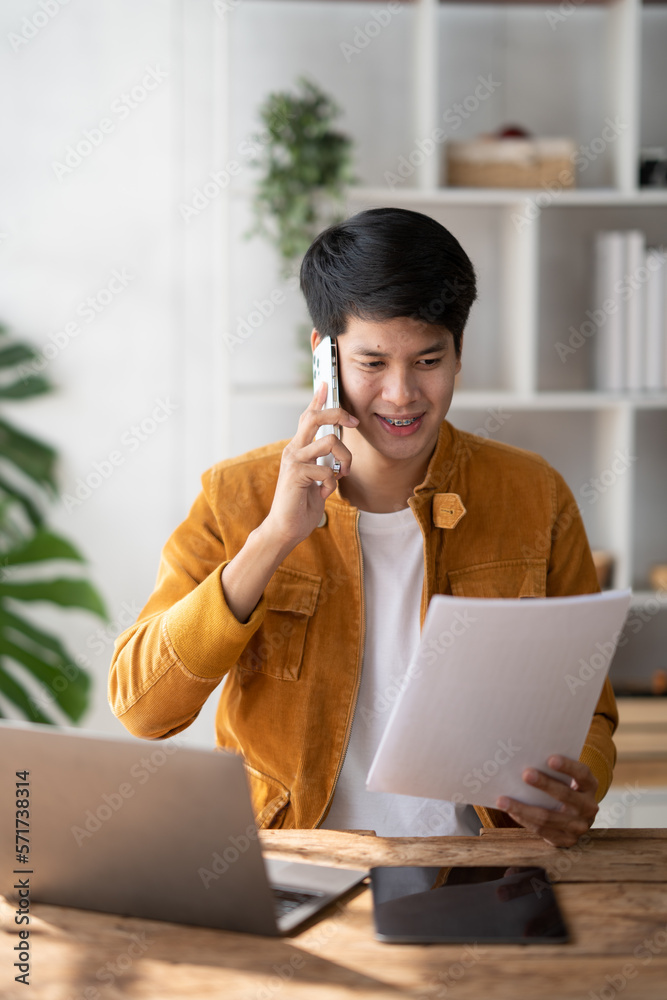 Portrait of young smiling cheerful entrepreneur in casual office making phone call while working wit