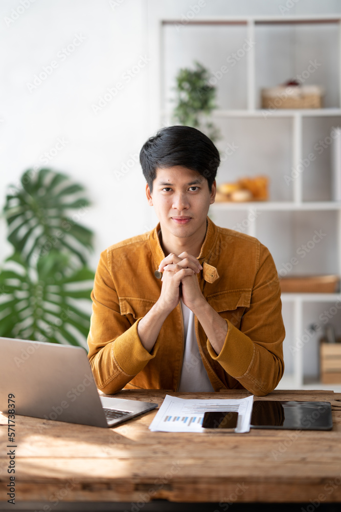 Young charming man working in the office room, smiling and looking at the camera.