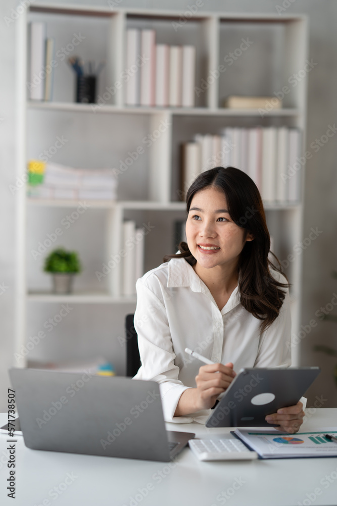 Young smart businesswoman writing her ideas on digital tablet while sitting in the modern office roo