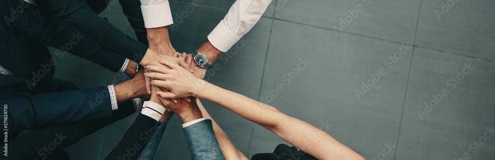 Diverse business team putting their hands together in a huddle of support and motivation