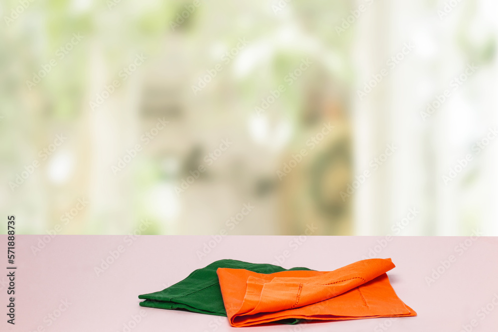 Empty table product. Closeup of a empty orange and green tablecloth or napkin on a bright table agai