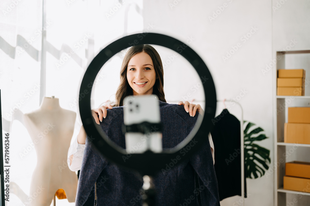 Beautiful Asian lady blogger showing clothes in front of the camera to recording vlog video live str