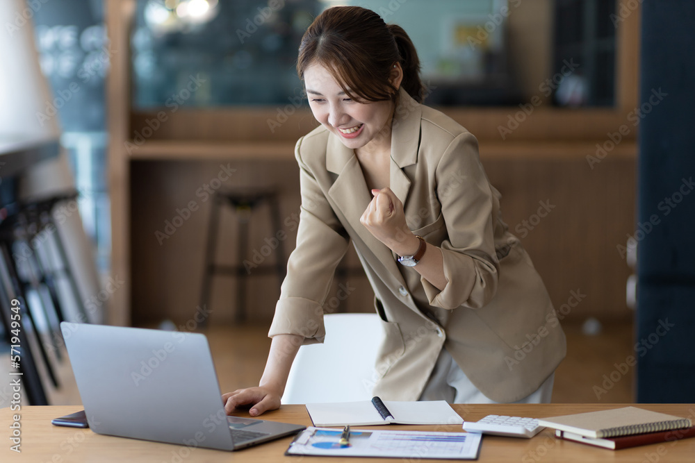 A business woman or secretary working on a laptop expresses her joy while looking at the laptop scre