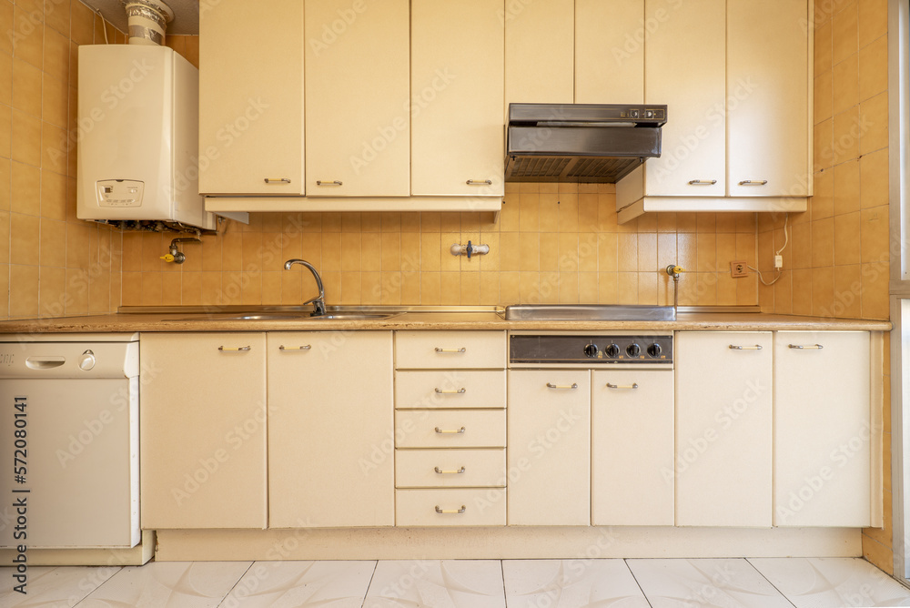 Frontal image of a kitchen with furniture with doors and drawers in cream-colored wood and light bro