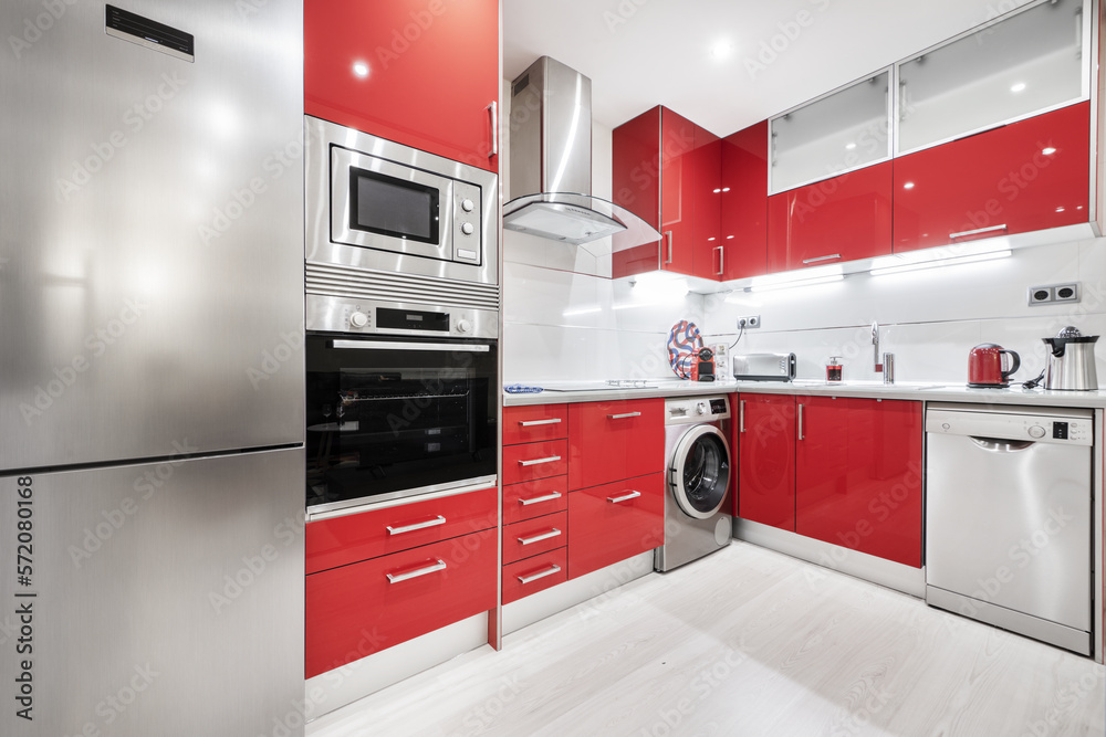 Furnished kitchen with two L-shaped walls with bright red cabinets, gray countertop and integrated s