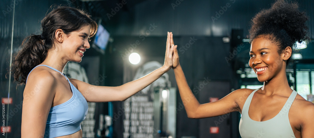 African and Latino sportswoman making high five after exercise in gym. 