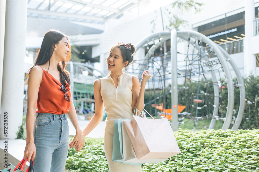 Asian two woman shopping goods outdoors in department store together.