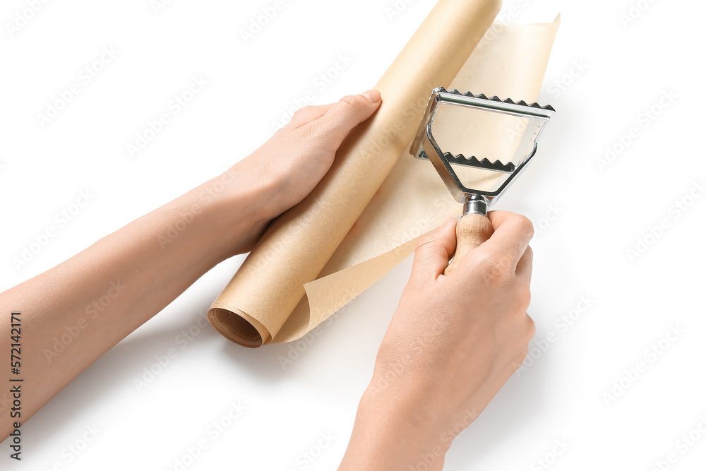 Female hands with roll of baking paper and ravioli cutter on white background, closeup