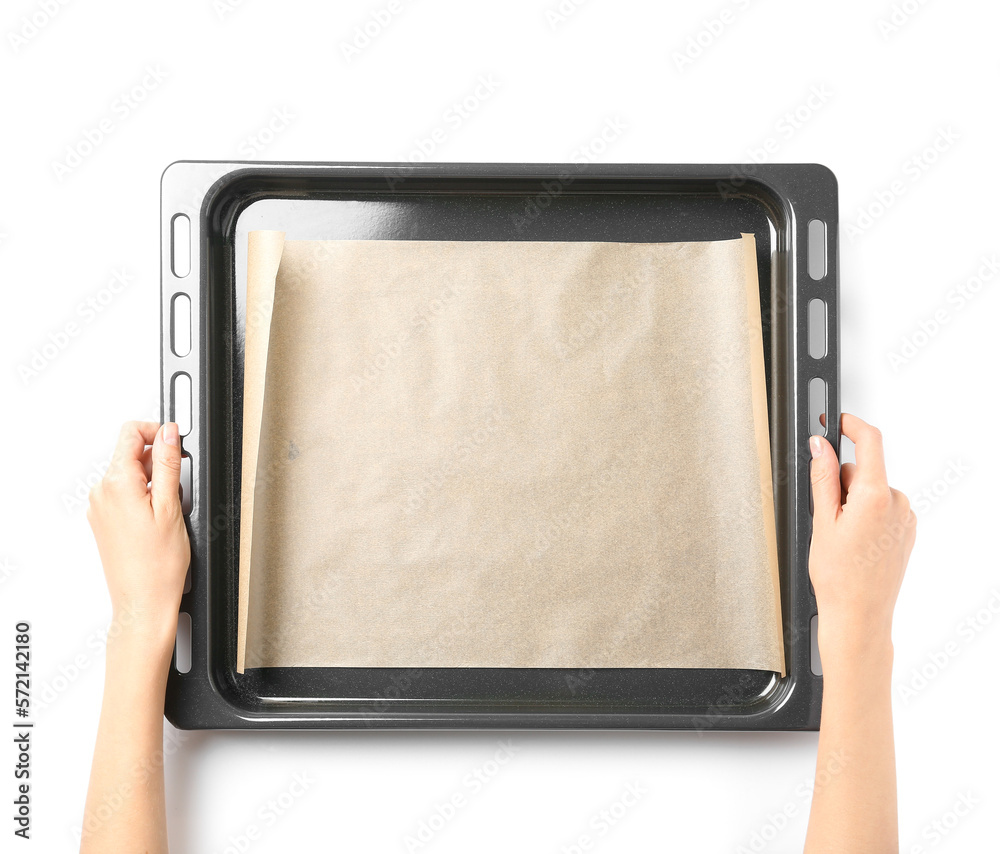 Woman holding baking sheet with paper on white background